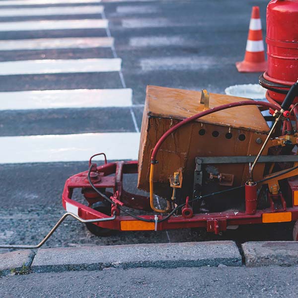 Process of making new road surface markings with a line striping machine, workers improve city infrastructure, demarcation marking of pedestrian crossing with a hot melted paint on asphalt pavement